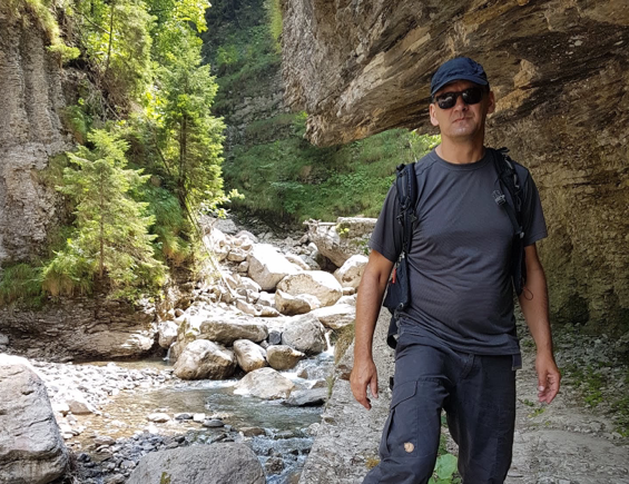 Mario Krenitz wandernd in den Bergen neben einem Felsen