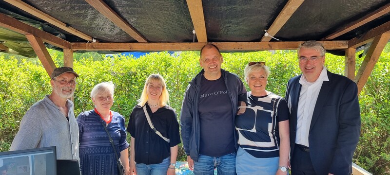 Hinter dem Tisch des überdachten Standes stehen von links nach rechts: Jörg Sorge, Vorsitzender, Gabriele Sorge, stellvertretende Vorsitzende, Eva Maria Sorge, Daisyfizierung und Versand von Blindenhörzeitschriften, Mario Krenitz, Kassenwart, Beate Bernd, Standbetreuung, Marko Wolfram, Landrat.